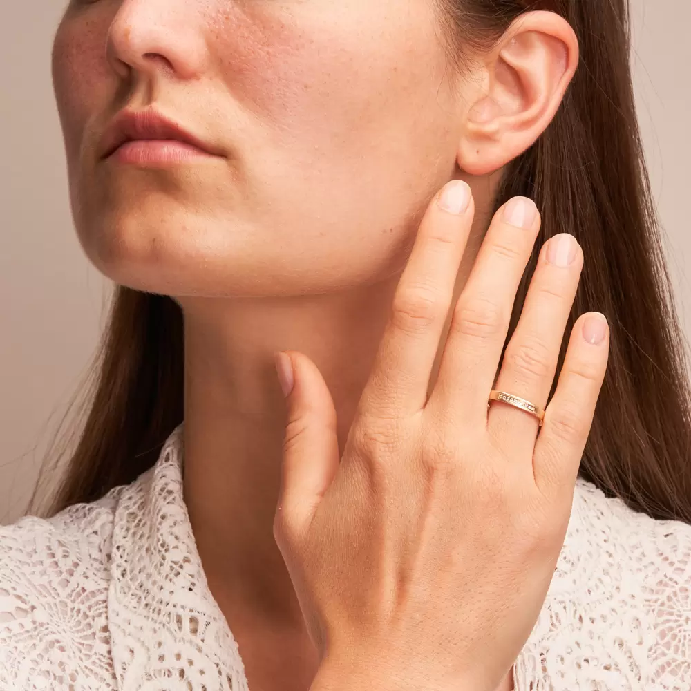 Außen flache Eheringe aus quermattem Sommergold mit Diamantenreihe auf Hand