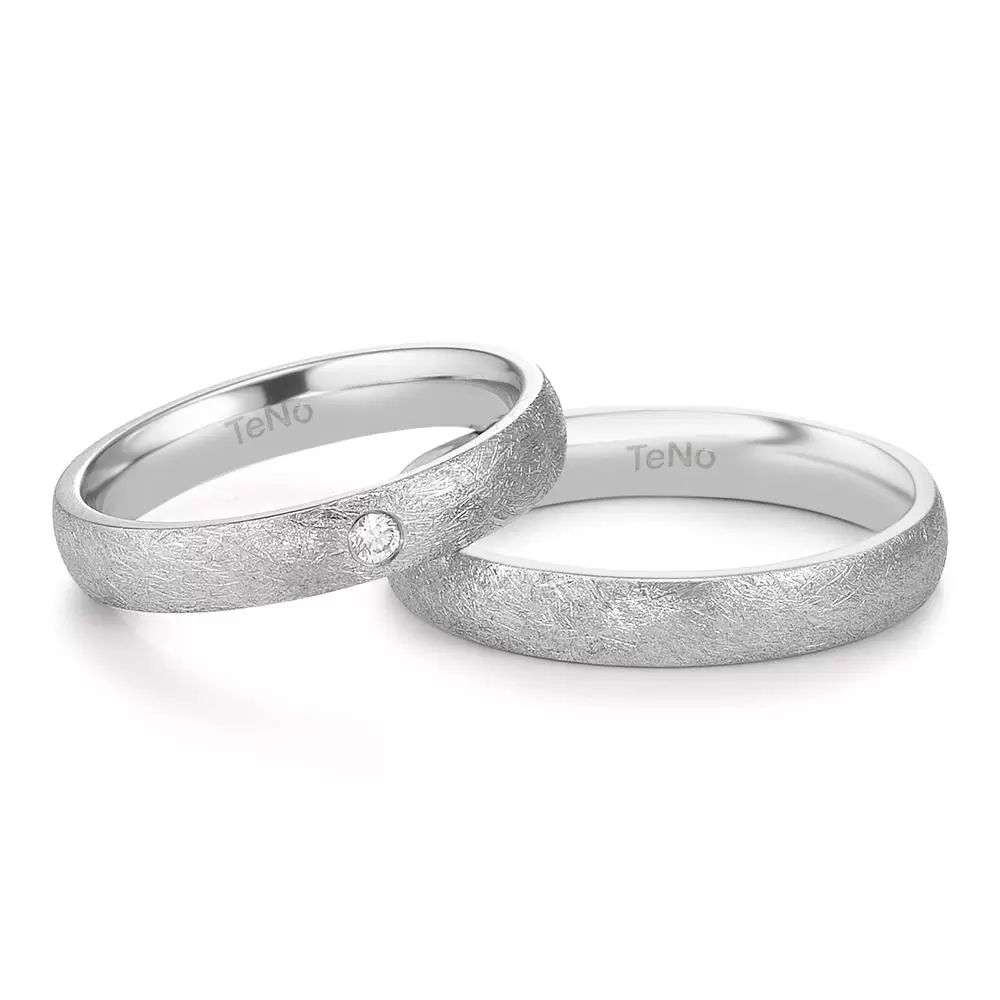 schmale Eheringe aus Edelstahl mit Diamanten und Eismattierung liegend