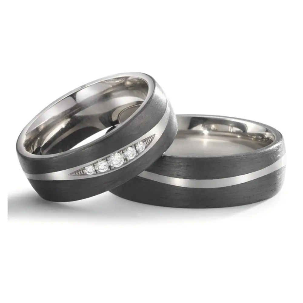 Titan Trauringe mit mehreren Diamanten und zwei Carbon Streifen liegend