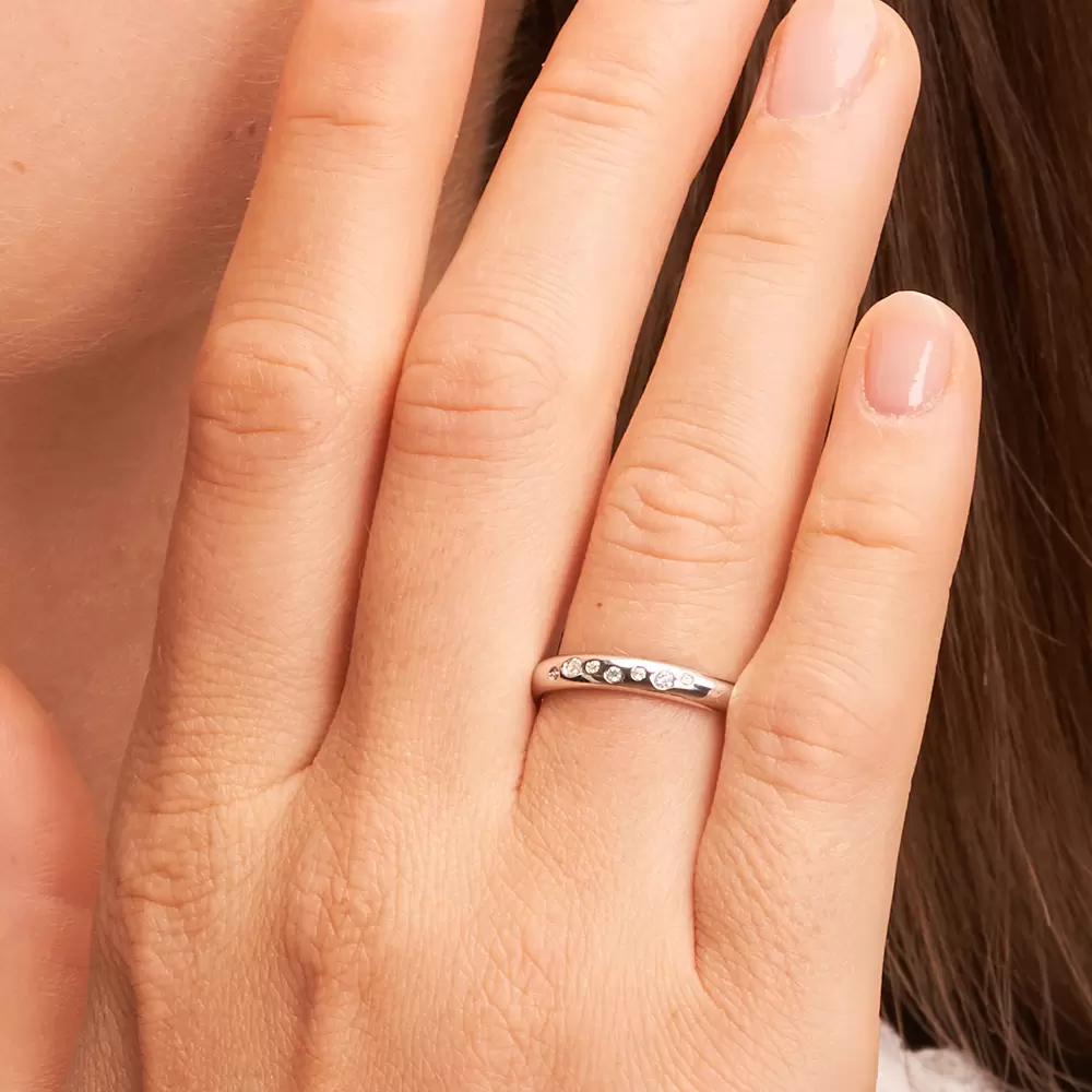 Eheringe aus poliertem Weißgold mit 7 Diamanten in Sternenhimmel Design auf Hand im Zoom