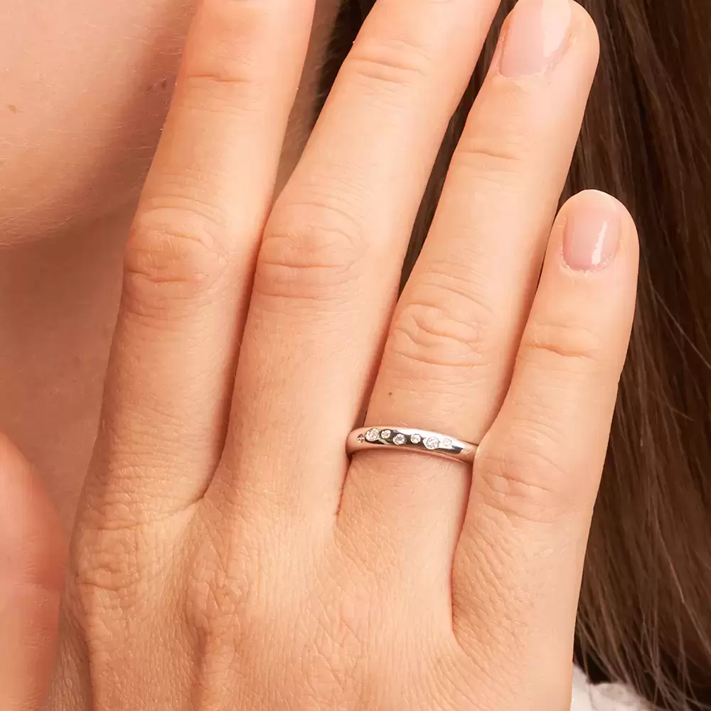 Eheringe aus poliertem Weißgold mit 7 Diamanten in Sternenhimmel Design auf Hand im Zoom