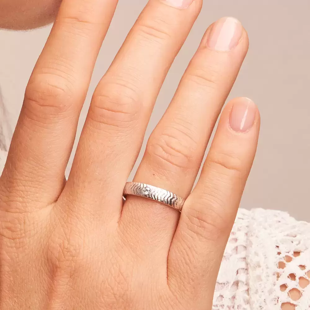 Eheringe aus strukturiertem Weißgold mit 0,04 Karat Diamanten auf Hand im Zoom
