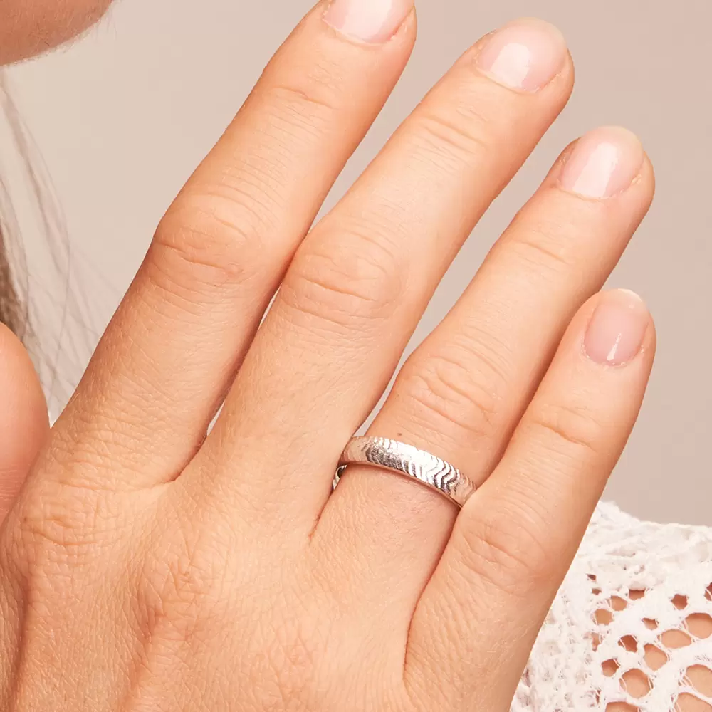 Eheringe aus strukturiertem Weißgold auf Hand im Zoom