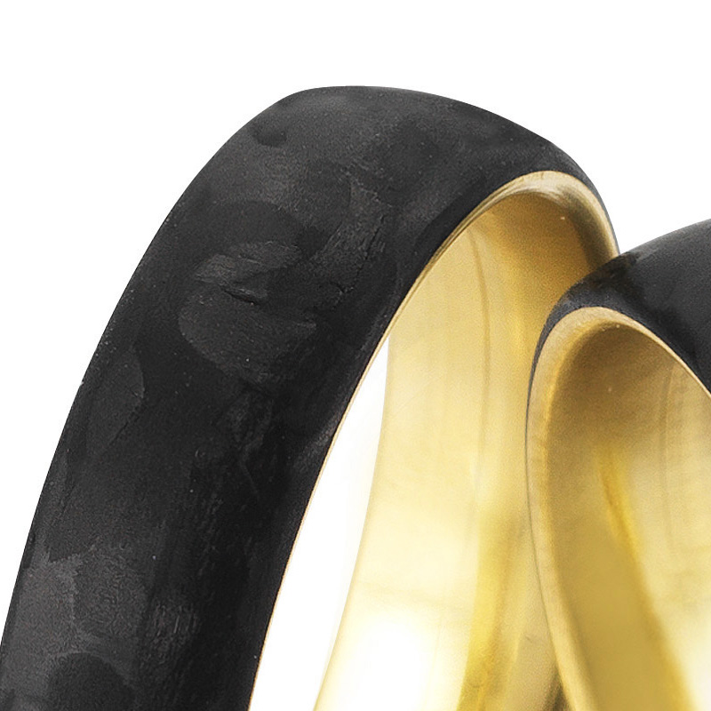 Aufnahme von gemaserten Eheringen aus Gelbgold&Carbon mit Diamanten in Sternenhimmel-Optik