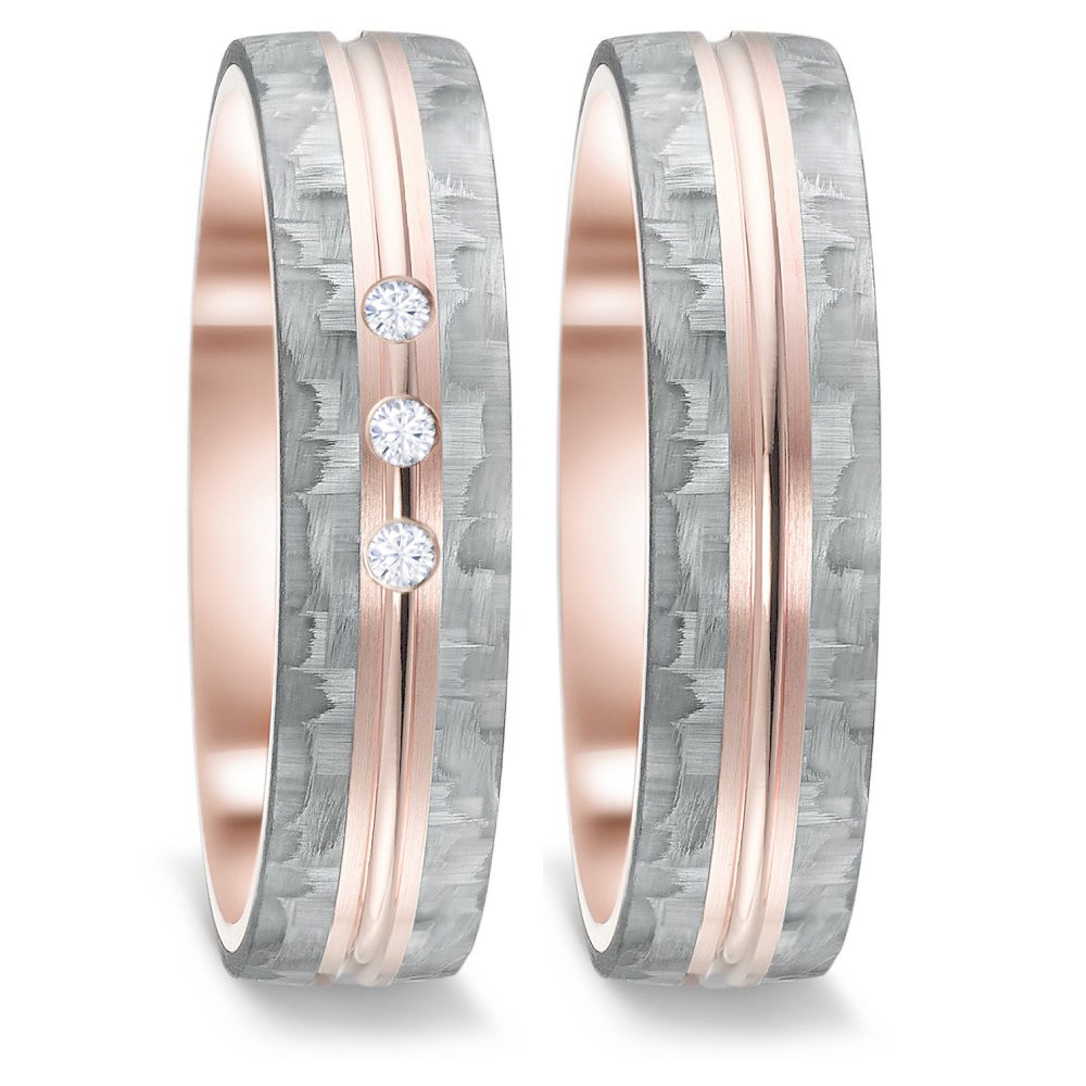 Frontale Aufnahme von Trauringen aus grauem Carbon mit drei Diamanten und Roségoldstreifen