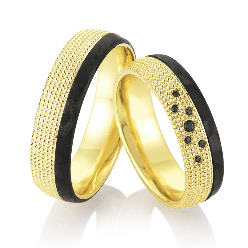 Aufnahme von taktilen Eheringe aus Gelbgold und Carbon mit Diamanten und Kreismuster