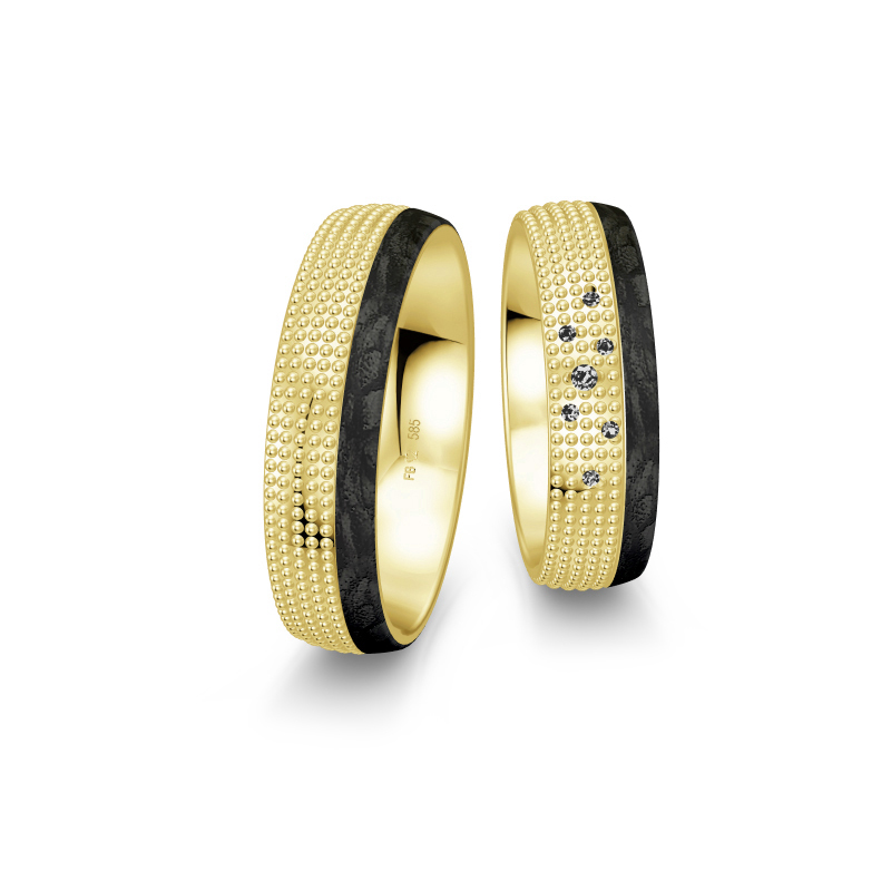 Aufnahme von taktilen Eheringe aus Gelbgold und Carbon mit Diamanten und Kreismuster 