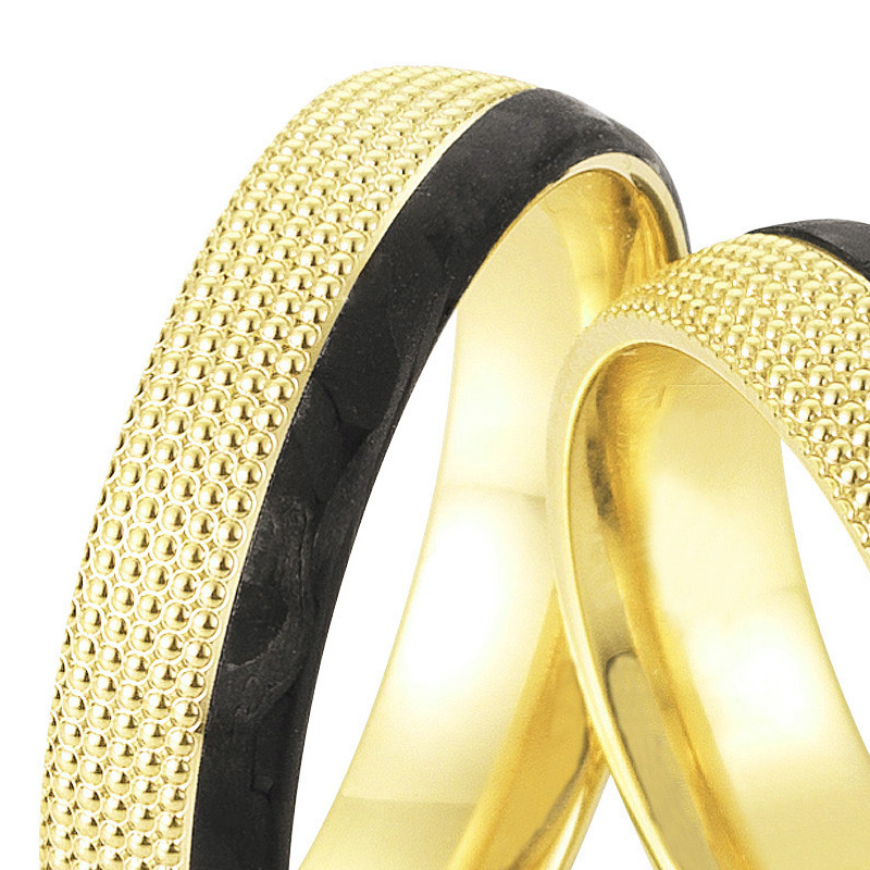 Aufnahme von taktilen Eheringe aus Gelbgold und Carbon mit Diamanten und Kreismuster