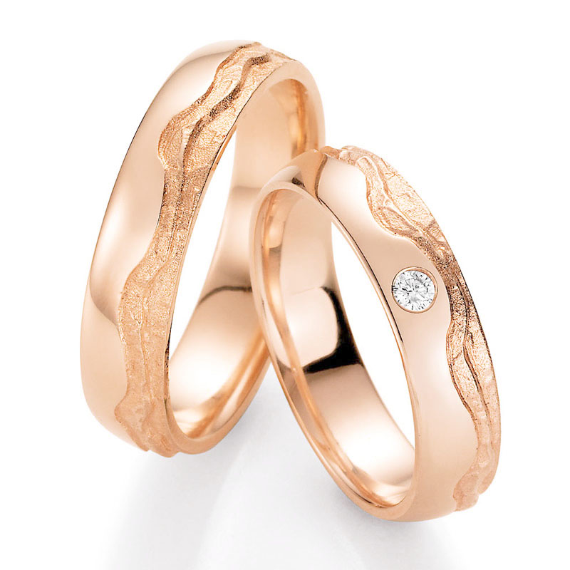 Aufnahme von Roségold Trauringen mit wellig designter Oberfläche und Diamanten 