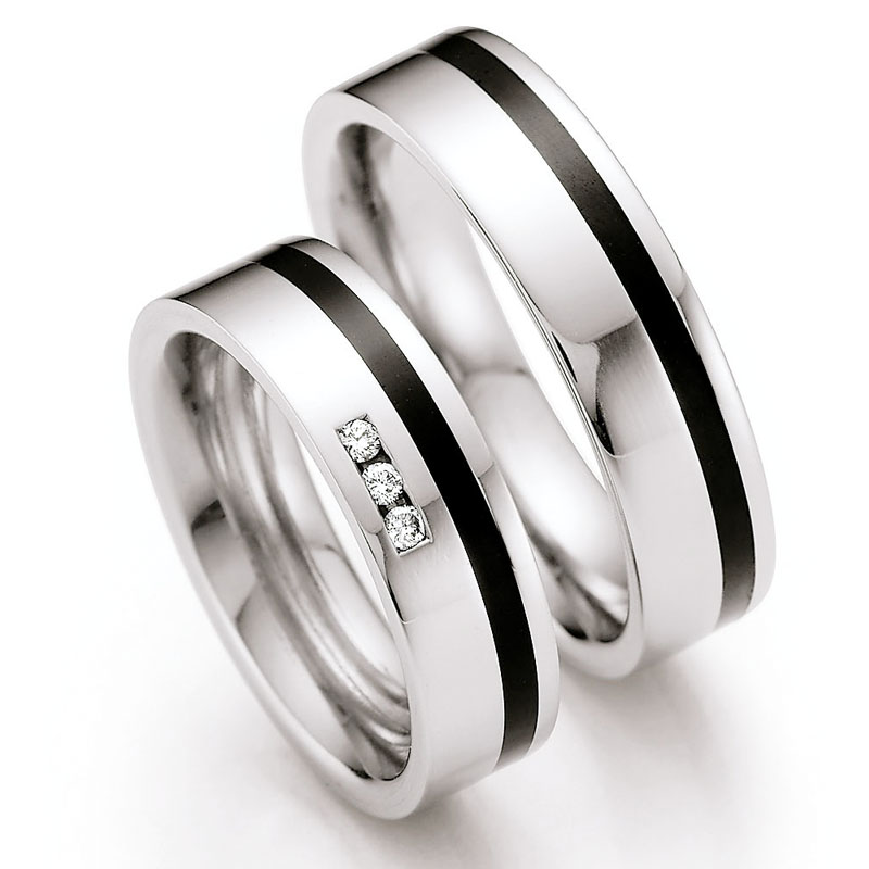 Frontale Aufnahme von flachen Eheringen aus Edelstahl mit schwarzem Keramikstreifen und Diamant 