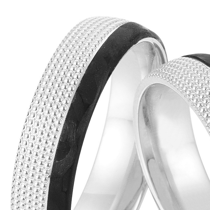 Aufnahme von taktilen Eheringe aus Weißgold und Carbon mit Diamanten und Kreismuster