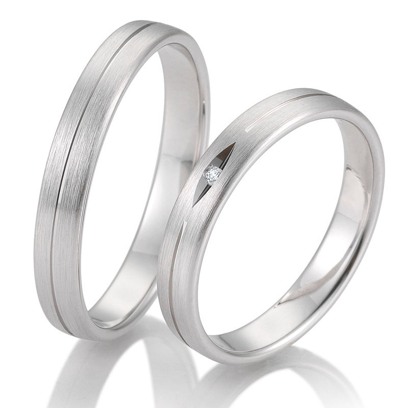 Seitliche Aufnahme von mattierten Trauringen aus Weissgold mit einem Diamanten in Vertiefung 
