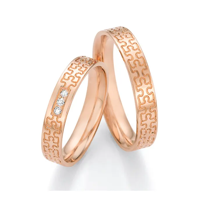 Rotgold Eheringe in Puzzle-Optik mit drei Diamanten in Reihe