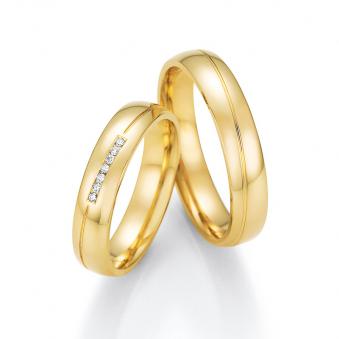 Aufnahme der Eheringe aus poliertem Gelbgold mit diagonaler Rille und 7 Diamanten in Kanalfassung