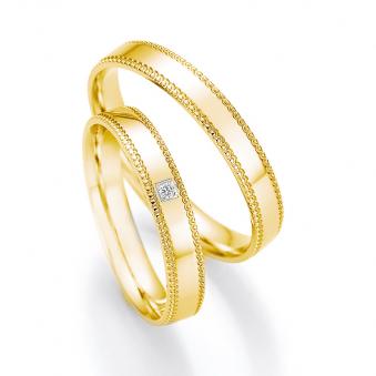 Aufnahme der Gelbgold Trauringe mit Schnörkel an Rändern und Diamanten in quadratischer Vertiefung 	