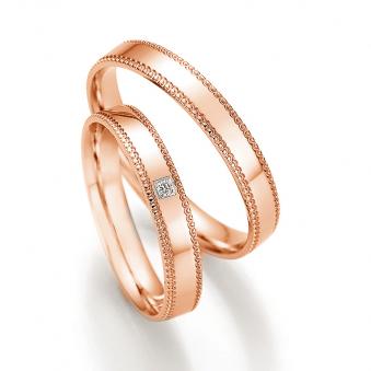 Aufnahme der Eheringe aus Rotgold mit Schnörkel an Rändern und Diamanten