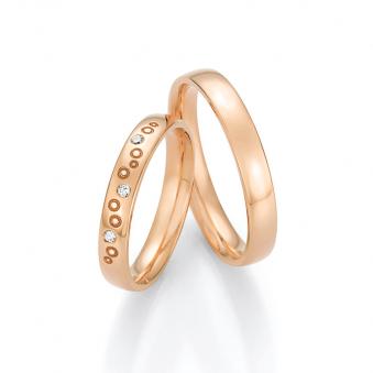 Aufnahme von Roségold Trauringen in Seifenblasen-Optik mit drei runden Diamanten