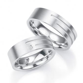 Aufnahme von breiten Trauringen aus Silber mit asymmetrisch angebrachtem Diamanten und Rillen 