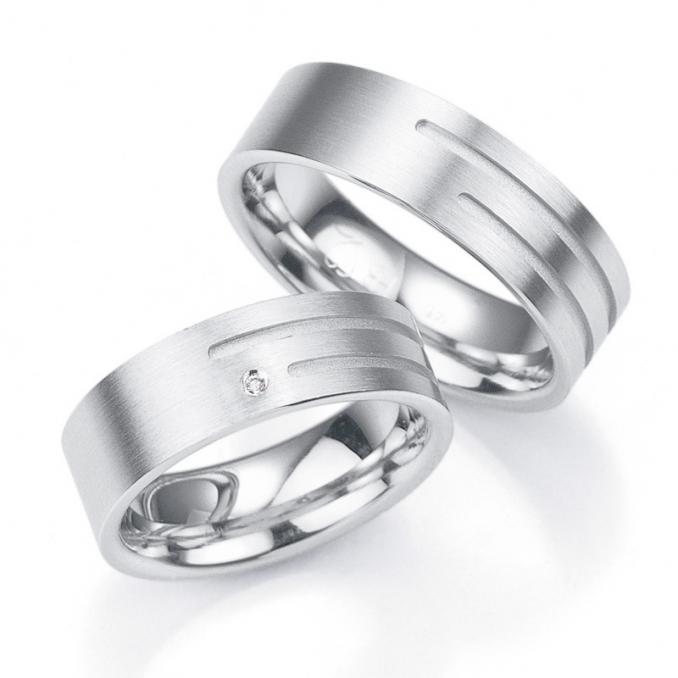 Aufnahme von breiten Trauringen aus Silber mit asymmetrisch angebrachtem Diamanten und Rillen