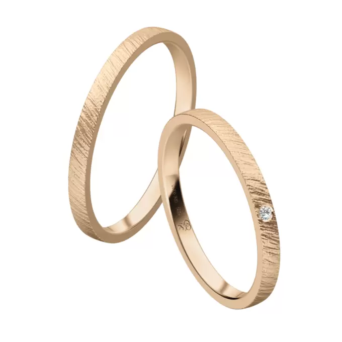 Schmale Eheringe aus Sommergold mit einzelnem Diamanten und schraffierter Oberfläche