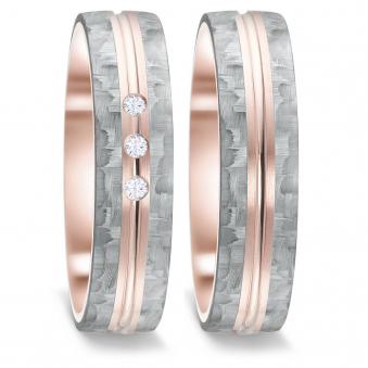 Frontale Aufnahme von Trauringen aus grauem Carbon mit drei Diamanten und Roségoldstreifen