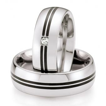 Frontale Aufnahme von flachen Eheringen aus Edelstahl mit 2 schwarzen Keramikstreifen und Diamant 