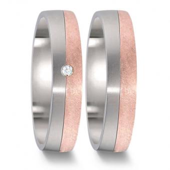 Frontale Aufnahme von Titan und Roségold Eheringen mit polierter und kratzmatter Flächen Diamanten