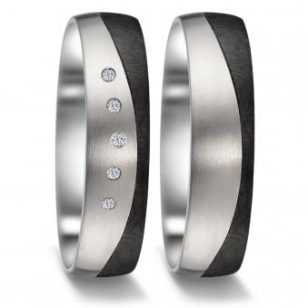 Frontale Aufnahme von Eheringen aus Titan und Carbon in geschwungenem Design mit fünf Diamanten