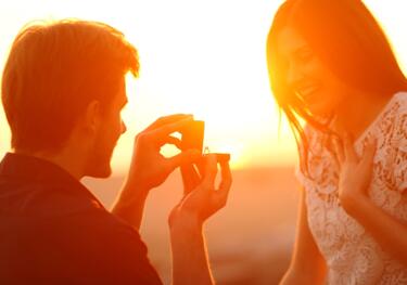 Hochzeitsantrag mit Ring am Strand im Sonnenuntergang