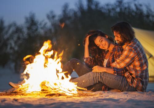 Paar sitzt vor lagerfeuer