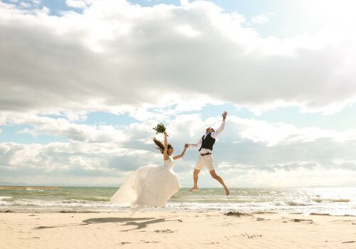 Brautpaar springt am Strand